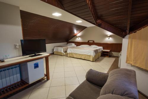 a hotel room with two beds and a tv at Hotel Fioreze Origem in Gramado