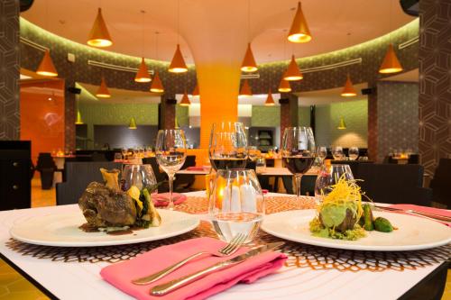 a table with two plates of food and glasses of wine at Temptation Cancun Resort - All Inclusive - Adults Only in Cancún
