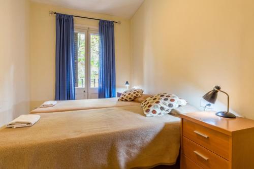 バルセロナにあるApartEasy - Sant Antoni Marketのベッドルーム1室(ベッド2台、青いカーテン付きの窓付)