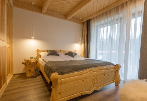 1 dormitorio con cama de madera y ventana grande en Apartament Leśny en Zakopane