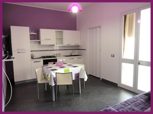 サン・ヴィート・ロ・カーポにあるNuovissima casa Vacanze a San Vito Lo Capoのキッチン(テーブル、椅子付)、紫の壁のキッチン