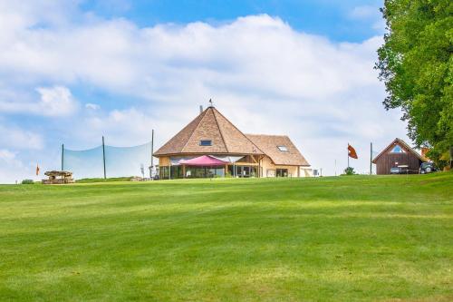 a large building on a grassy hill with a field at Golf de La Chassagne in Mâlain