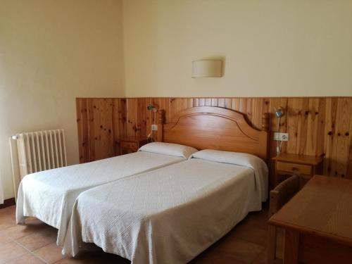 a bedroom with a large bed with white sheets at Hostal La Catalana in Sant Llorenc de Morunys