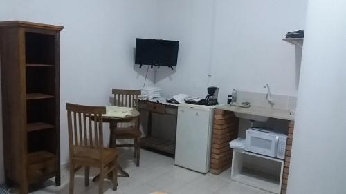 una pequeña cocina con mesa y TV en CHALÉ da LÚ ILHABELA, en Ilhabela