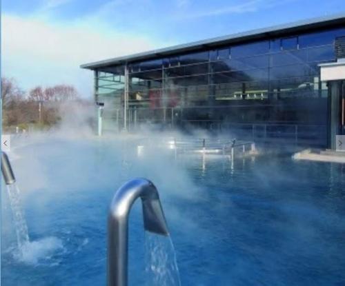 une piscine d'eau en face d'un bâtiment dans l'établissement BaMeS BadUrach Metzingen Stuttgart, à Bad Urach