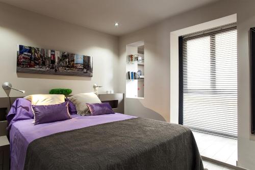 a bedroom with a bed with purple sheets and a window at Elegant Eixample Apartment nicely decorated in Barcelona