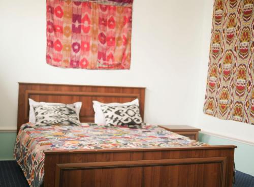 een slaapkamer met een bed en een gordijn bij Guest House Ikathouse in Margilan