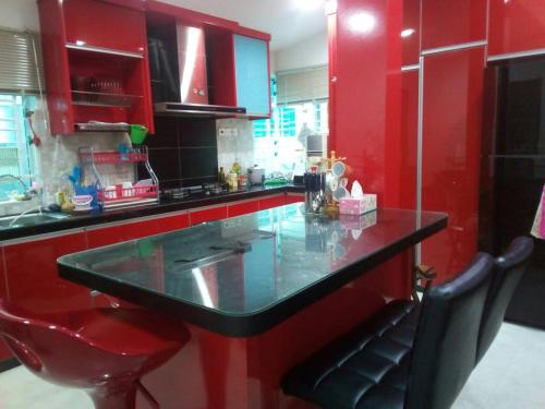 a red kitchen with a black counter and red cabinets at Villa Fairuz Hana Islamic Stay in Kangar
