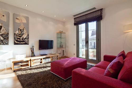 a living room with a red couch and a tv at You Stylish El Borne Apartments in Barcelona