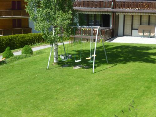 a swing set in a yard with a tree at Ferienwohnung Edelweiss in Grächen