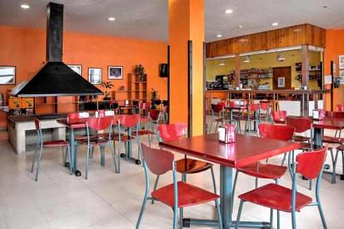 ein Restaurant mit roten Stühlen und Tischen und einer Bar in der Unterkunft Albergue Era Garona in Salardú
