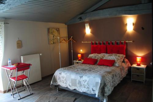 a bedroom with a large bed with red pillows at La Poussardiere in Saint-Martin-sous-Mouzeuil