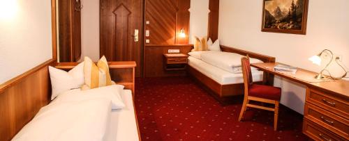 a hotel room with two beds and a desk at Hotel Post Kappl in Kappl