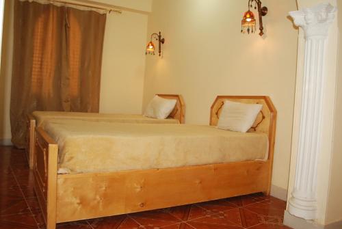 a bedroom with a wooden bed with two pillows at Arabesque House Apartment in Luxor