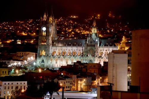 a large building with a clock tower at night at La Rosario Hotel in Quito