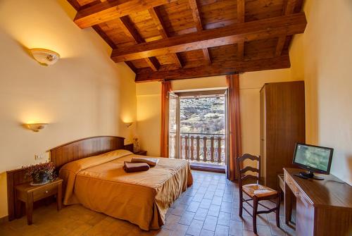 a bedroom with a bed and a desk and a window at Ginepro d'Abruzzo in Casamaina