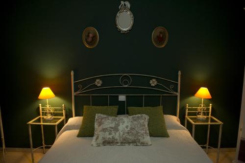 een slaapkamer met een bed met groene muren en 2 lampen bij Casa Rural La Biblioteca in Almagro
