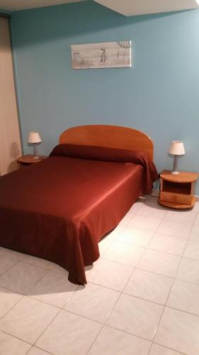 Bett in einem Zimmer mit 2 Tischen und 2 Lampen in der Unterkunft Hostellerie des Colonnes in La Force
