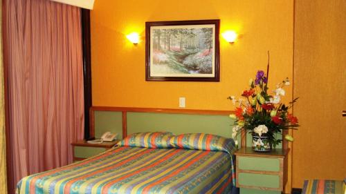 a hotel room with a bed and a vase of flowers at Segovia Regency in Mexico City