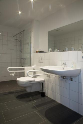 a bathroom with a sink and a toilet and a mirror at Ruhr Inn Hotel in Hattingen