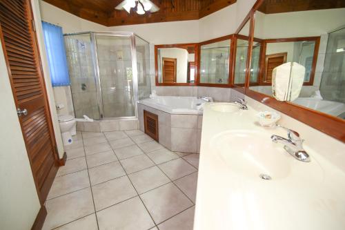 a bathroom with a tub and a sink and a shower at Coco La Palm in Negril