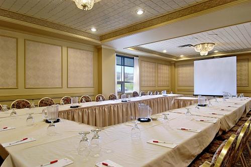 a conference room with tables and chairs and a screen at Ramada by Wyndham St. John's in St. John's