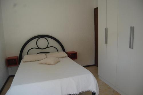 a bedroom with a white bed with two pillows at Pousada Santa Genoveva campeche in Florianópolis