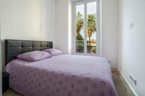a bedroom with a bed with a purple comforter and a window at Carré d'OR! Park view! in Nice
