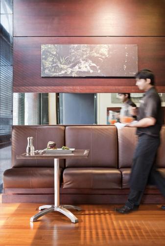a man standing in front of a couch with a table at ibis Wellington in Wellington