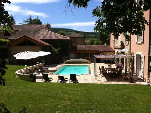 a pool in a yard with chairs and an umbrella at La Maison du Parc in Yzeron