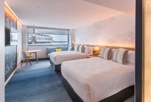 a hotel room with two beds and a desk at M Social Auckland in Auckland