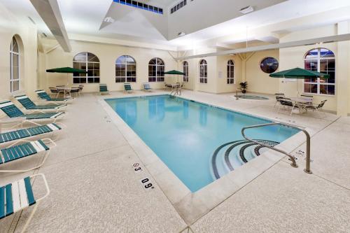 a pool in a hotel with chairs and tables at Hawthorn Suites by Wyndham Louisville East in Louisville