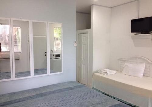 a white bedroom with a bed and a tv on the wall at The Oasis Retreat in Nassau