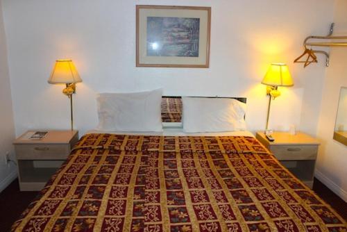 a bedroom with a bed with two lamps and two tables at Beacon Motel in Long Beach