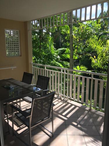 a balcony with a table and chairs on a porch at Cairns Golf Course Apartment in Cairns