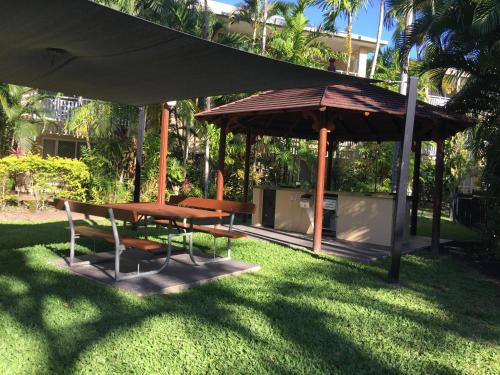 a picnic table and an umbrella in a yard at Cairns Golf Course Apartment in Cairns