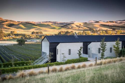 a white building with a black roof next to a vineyard at Black Estate B & B in Waipara