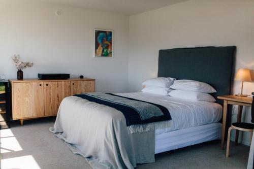 a bedroom with a bed with a green headboard and a table at Black Estate B & B in Waipara