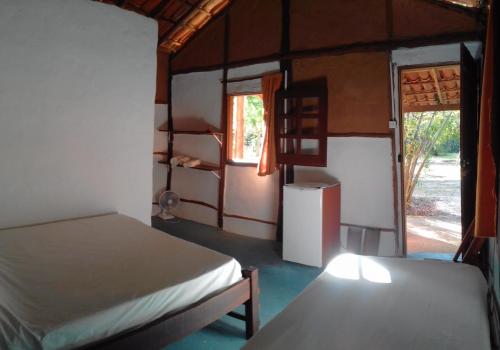 a small room with two beds and a refrigerator at Pousada Aldeia de Morere in Moreré
