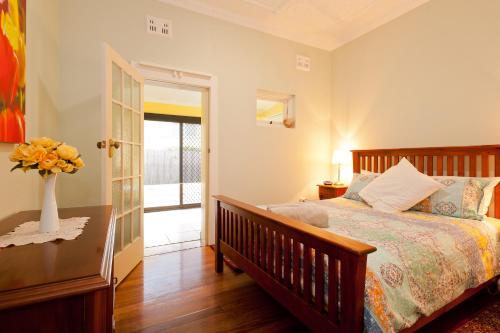 1 dormitorio con 1 cama y un jarrón de flores sobre una mesa en Taree Apartment en Taree