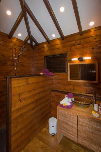 a wooden bathroom with a sink and a tub at Le matelot de la baie in Deshaies