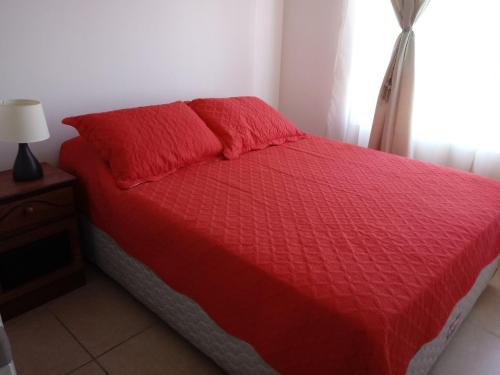 1 dormitorio con cama roja y edredón rojo en Marina Sol, en Coquimbo
