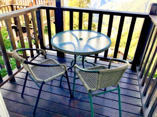 a glass table and two chairs on a deck at Home Box in Renai