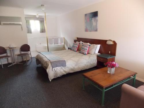 a bedroom with a bed and a table and a couch at Yass Motel in Yass