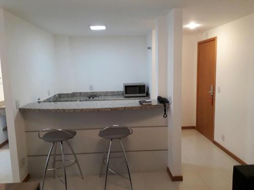 a kitchen with two stools and a counter with a microwave at Flat no Prime Residence in Itaboraí