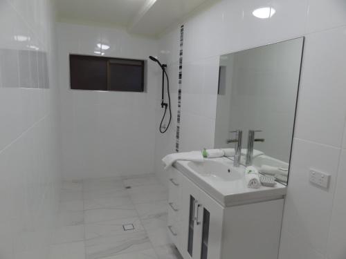 a white bathroom with a sink and a mirror at The Gums Anchorage in Bellara