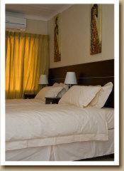 a bedroom with a large white bed with yellow curtains at Gannet Place Guest House in Hazyview