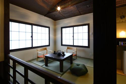 a room with a table and two chairs and two windows at Machiya Kaemon in Kyoto