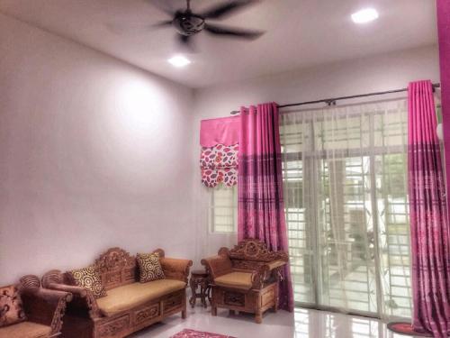 - un salon avec deux chaises et un ventilateur de plafond dans l'établissement Wadihana Homestay, à Kangar