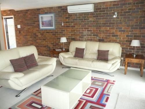 a living room with two white couches and a brick wall at The Gums Anchorage in Bellara